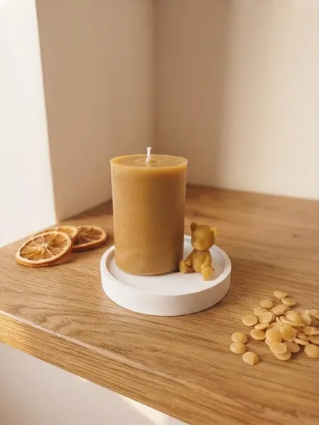 Vela de cera de abeja artesanal con figura de osito, sobre platillo de yeso